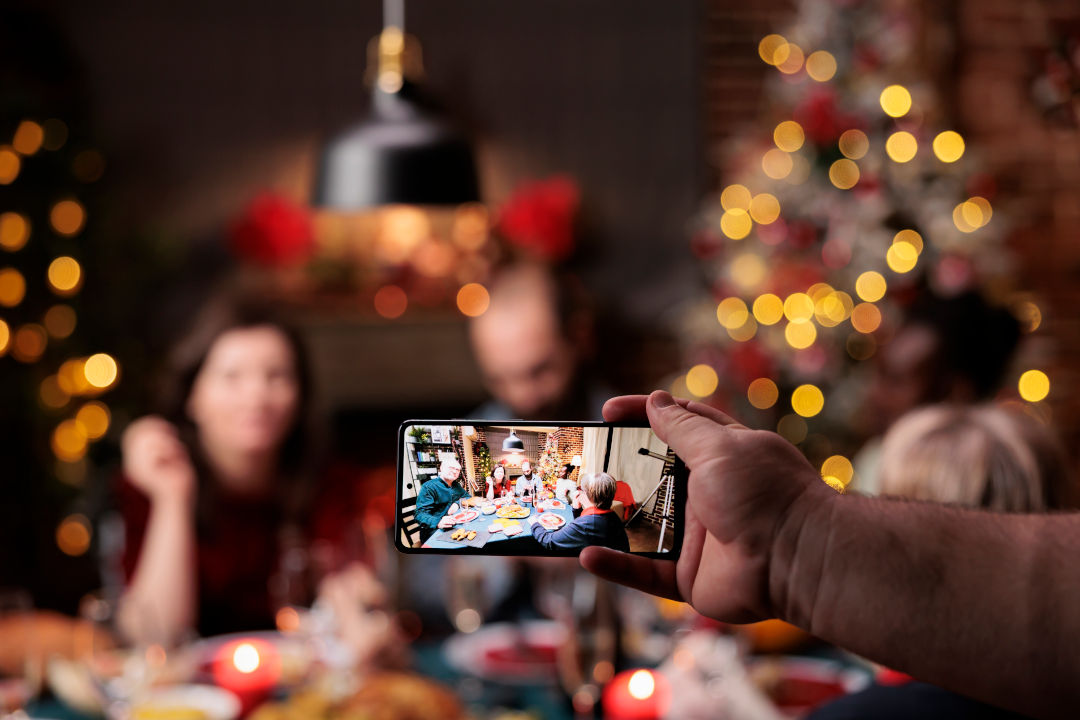 person takes photos of people at table